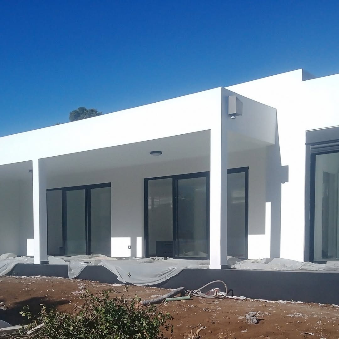 Maison contemporaine blanche à toit plat construite par CASE INOV, baies vitrées noires
